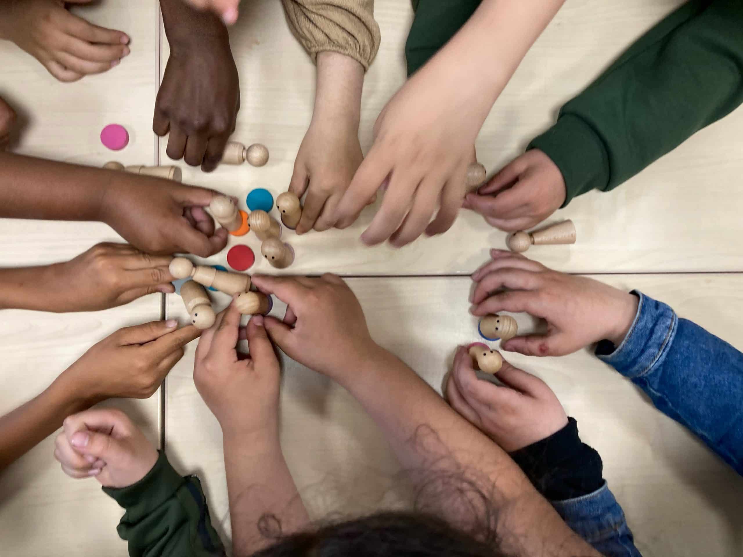 Kinderen plaatsen symbolisch hun poppetjes op tafel tijdens een Levend Sociogram, waarmee ze de onderlinge groepsdynamiek zichtbaar maken