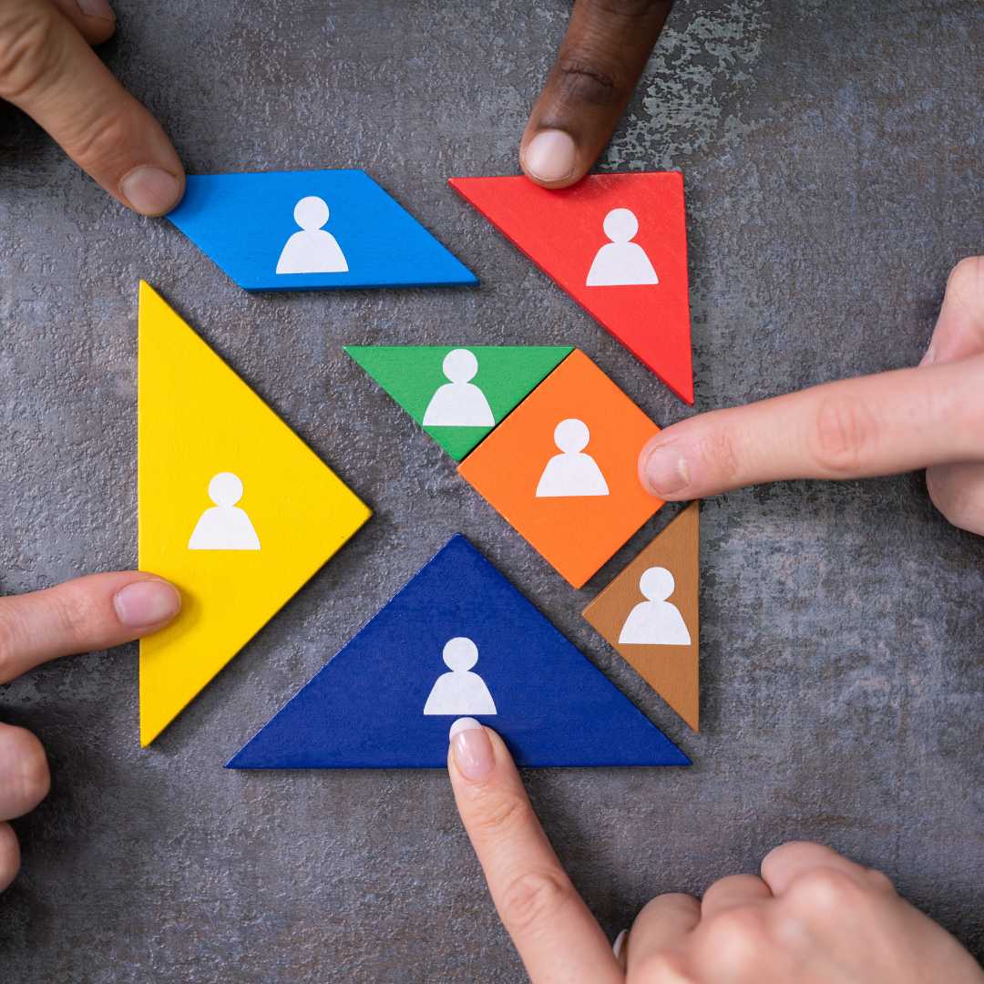 Handen plaatsen kleurrijke vormen met pictogrammen van personen op een tafel.